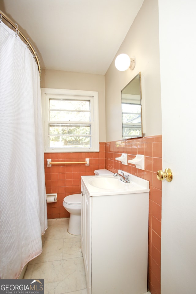 bathroom featuring vanity, toilet, and tile walls