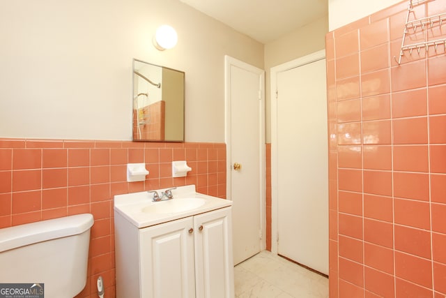 bathroom with toilet, vanity, and tile walls