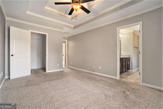 unfurnished bedroom with light carpet, a tray ceiling, and ornamental molding