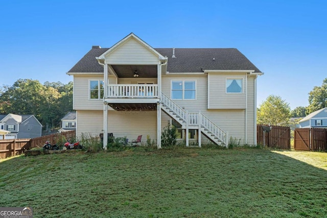 rear view of house featuring ceiling fan and a lawn