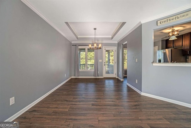 interior space featuring a notable chandelier, ornamental molding, a tray ceiling, and dark hardwood / wood-style flooring