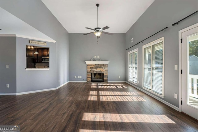 unfurnished living room featuring ceiling fan, a stone fireplace, and dark hardwood / wood-style flooring