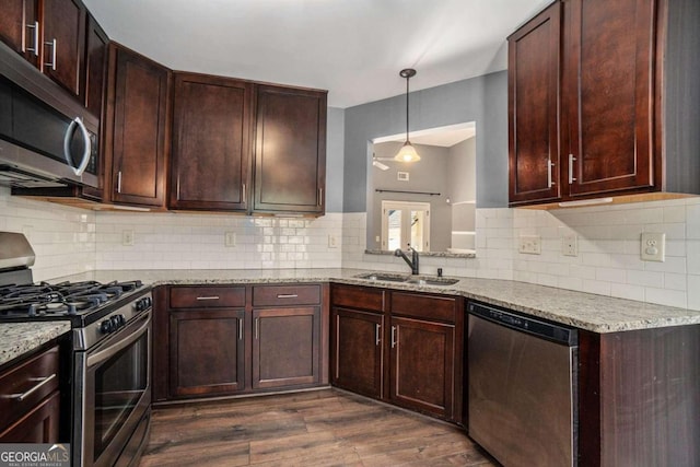 kitchen with light stone counters, stainless steel appliances, tasteful backsplash, sink, and dark hardwood / wood-style flooring