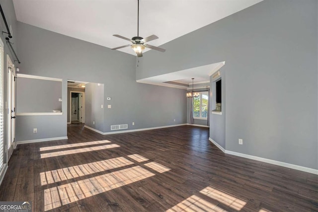 unfurnished living room featuring ceiling fan with notable chandelier, high vaulted ceiling, a barn door, and dark wood-type flooring