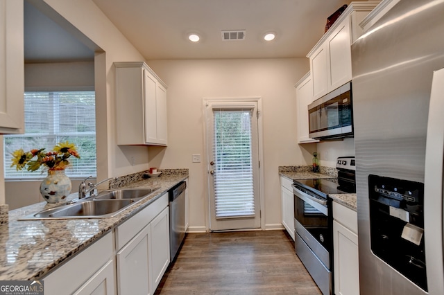 kitchen featuring stainless steel appliances, hardwood / wood-style floors, white cabinetry, and a wealth of natural light