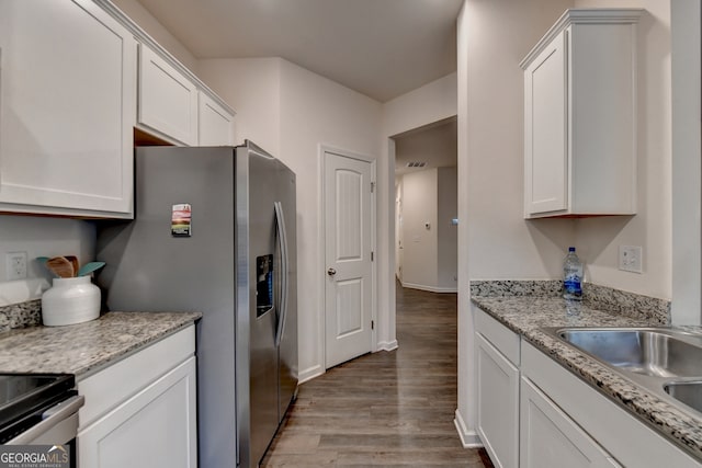 kitchen with light hardwood / wood-style floors, appliances with stainless steel finishes, light stone counters, and white cabinetry