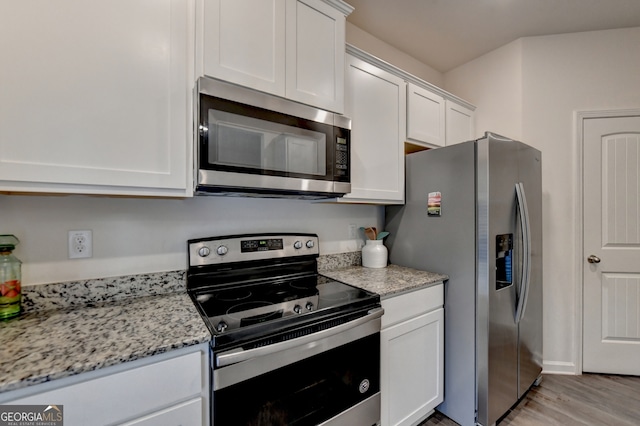 kitchen featuring appliances with stainless steel finishes, light hardwood / wood-style flooring, light stone counters, and white cabinetry