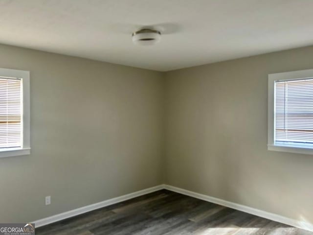 unfurnished room featuring plenty of natural light and dark wood-type flooring