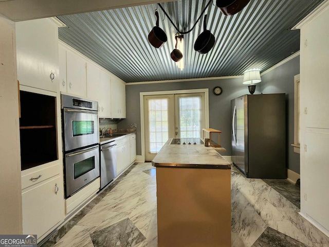 kitchen with appliances with stainless steel finishes, french doors, ornamental molding, and white cabinets