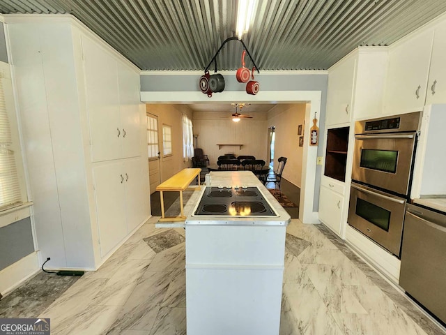 kitchen with stainless steel appliances, ornamental molding, white cabinets, and a center island