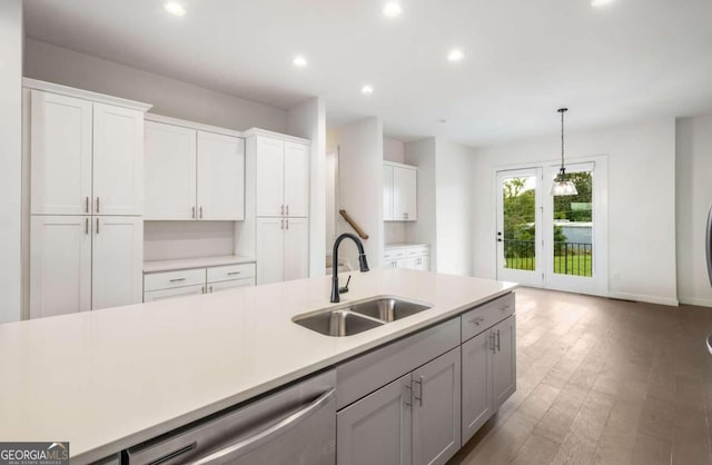 kitchen featuring white cabinets, hanging light fixtures, sink, stainless steel dishwasher, and dark hardwood / wood-style flooring