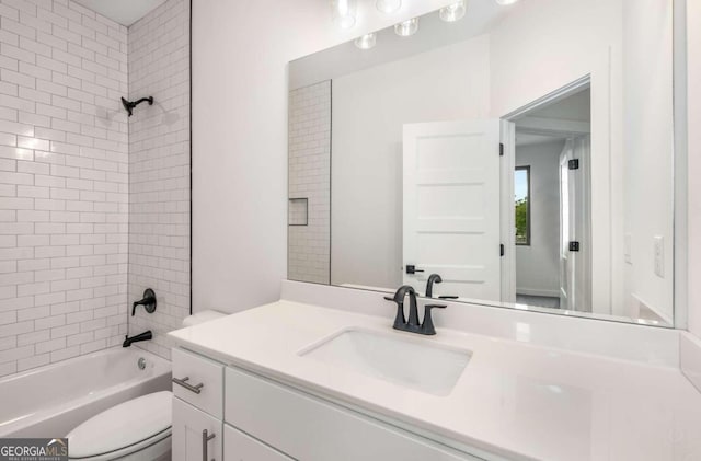 full bathroom featuring tiled shower / bath, vanity, and toilet