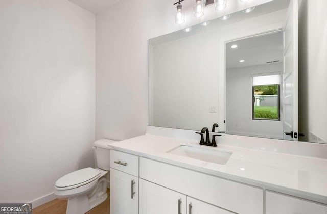 bathroom with hardwood / wood-style flooring, vanity, and toilet