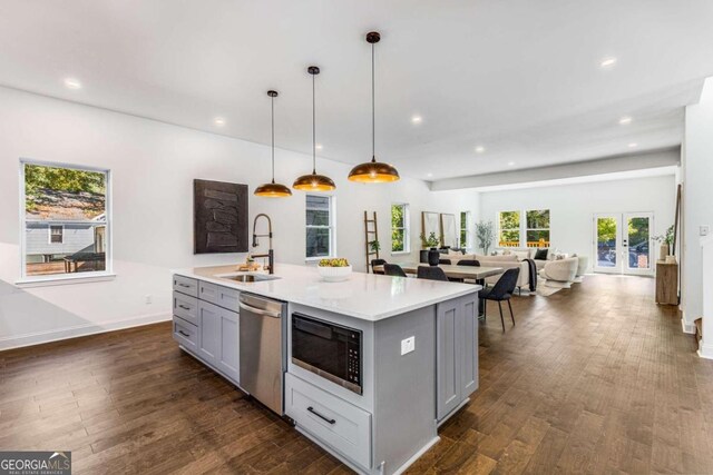 kitchen with sink, decorative light fixtures, a center island with sink, dishwasher, and black microwave