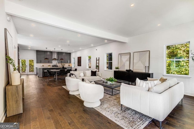 living room featuring beam ceiling, plenty of natural light, and dark hardwood / wood-style floors