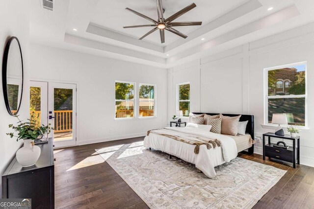 bedroom featuring ceiling fan, a tray ceiling, access to exterior, and dark hardwood / wood-style flooring