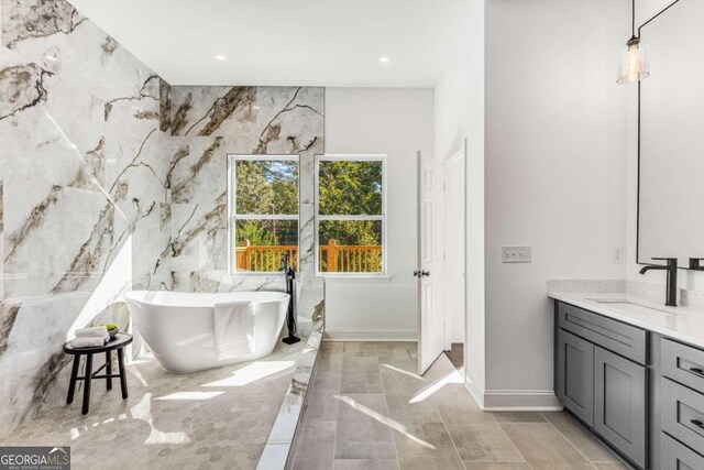 bathroom featuring vanity, a bathtub, and tile walls