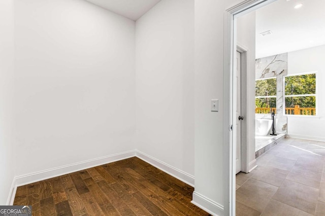 hallway with visible vents, baseboards, and wood finished floors