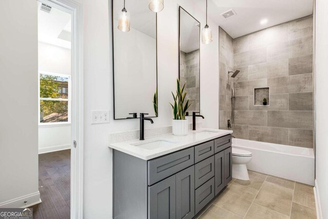 full bathroom featuring hardwood / wood-style flooring, vanity, toilet, and tiled shower / bath combo