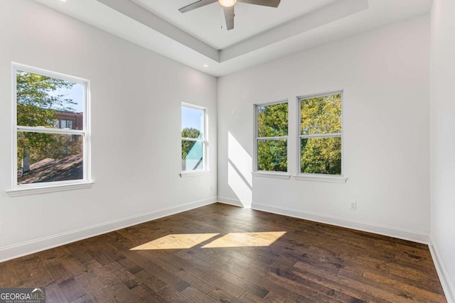 spare room with dark wood-style floors, baseboards, a ceiling fan, and a tray ceiling