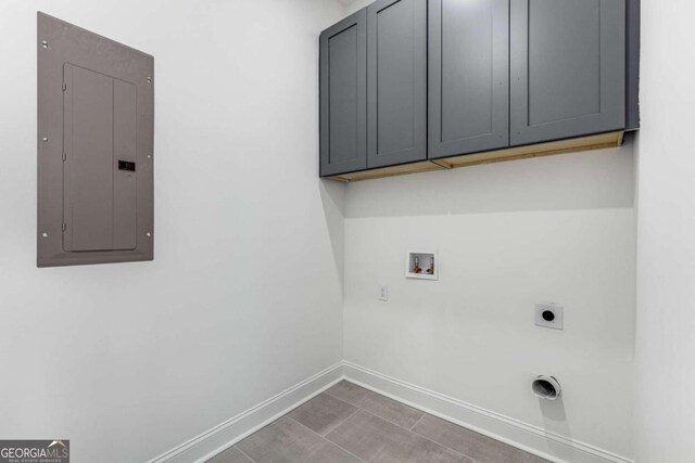 washroom with electric panel, hookup for an electric dryer, hookup for a washing machine, and cabinets