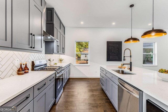 kitchen with pendant lighting, appliances with stainless steel finishes, sink, and gray cabinetry