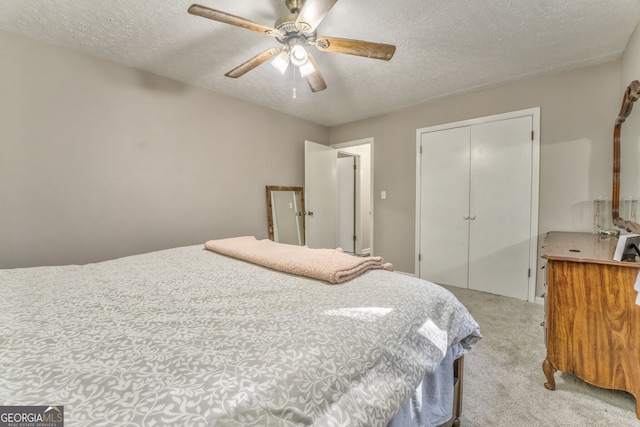 bedroom with a textured ceiling, ceiling fan, a closet, and light colored carpet