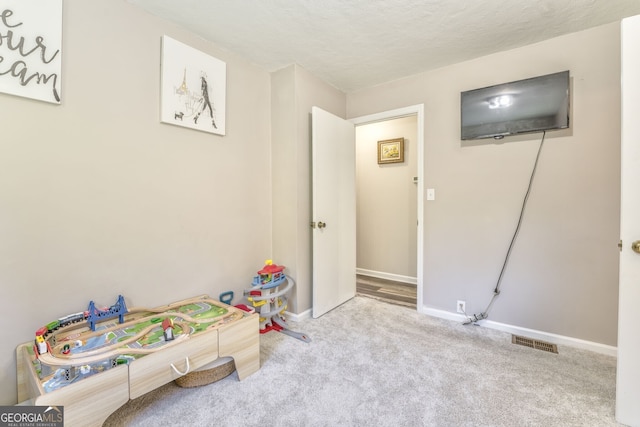 recreation room with light carpet, baseboards, visible vents, and a textured ceiling