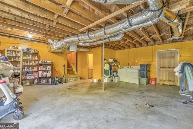 below grade area featuring stairway, concrete block wall, and washer and dryer