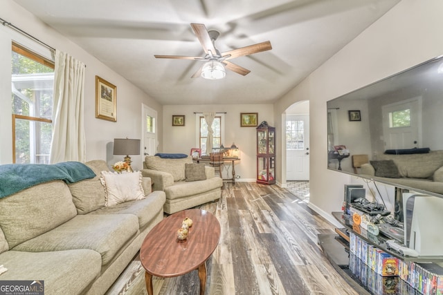 living room featuring wood finished floors, healthy amount of natural light, ceiling fan, and arched walkways
