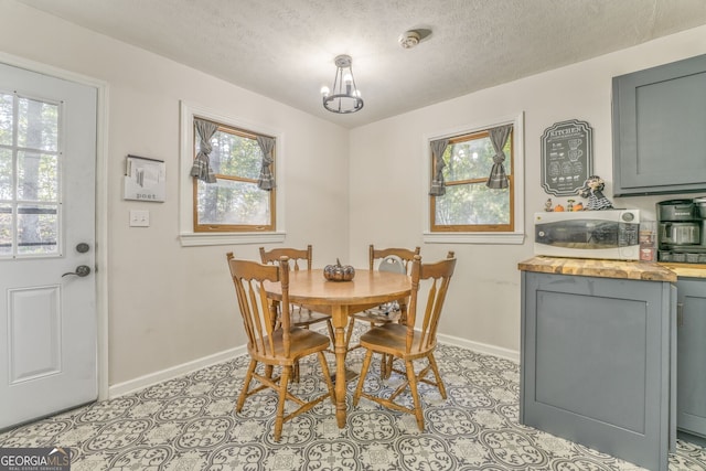 dining area with light tile patterned floors, a textured ceiling, baseboards, and a wealth of natural light