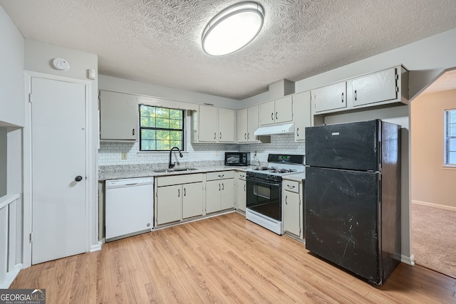 kitchen with backsplash, sink, black appliances, a textured ceiling, and light hardwood / wood-style floors