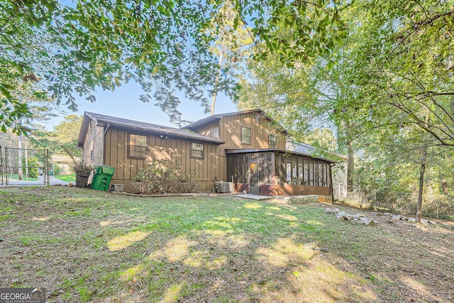 back of house with central AC, a lawn, and a sunroom