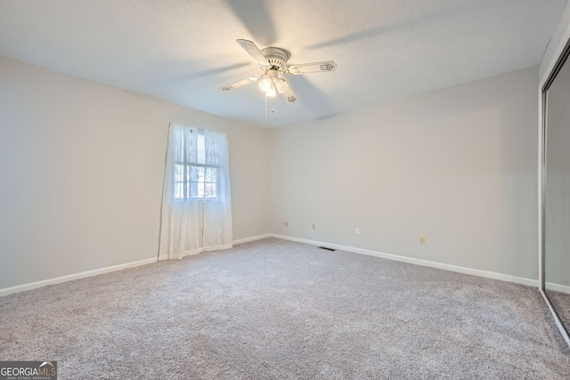 carpeted spare room featuring a textured ceiling and ceiling fan