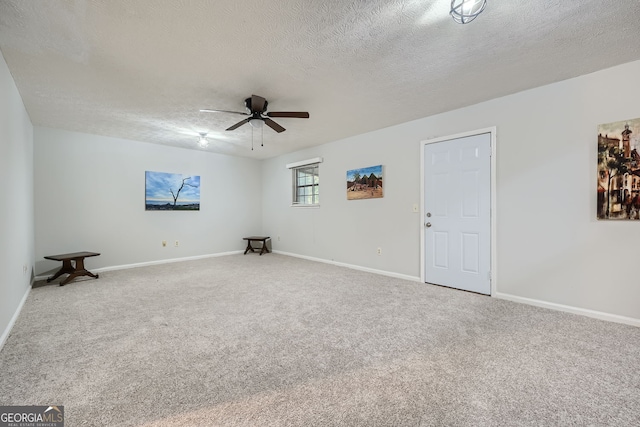 empty room featuring a textured ceiling, carpet floors, and ceiling fan