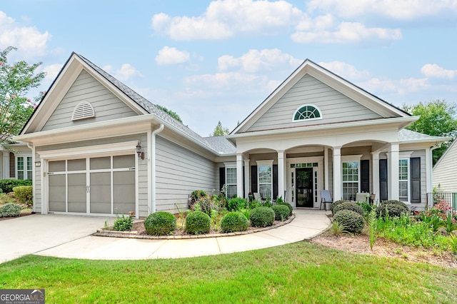 view of front of property featuring a garage, a porch, and a front lawn