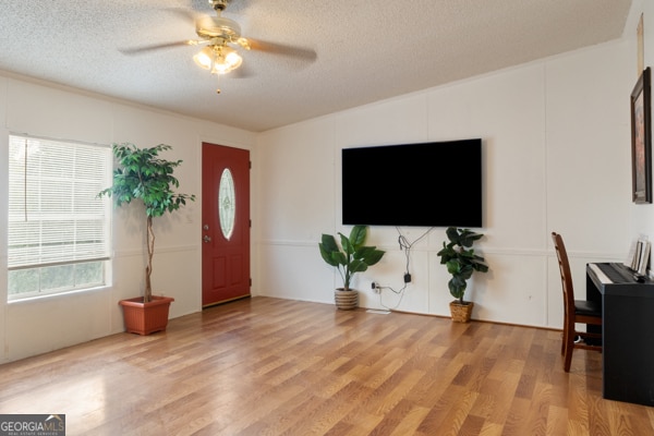 entrance foyer with light hardwood / wood-style floors, a textured ceiling, and ceiling fan