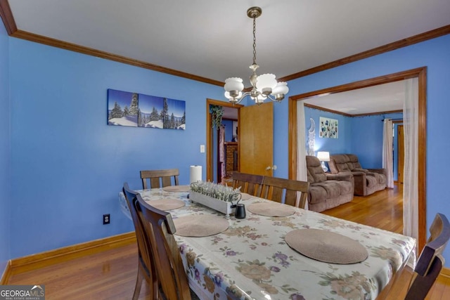 dining room featuring crown molding, an inviting chandelier, and wood-type flooring