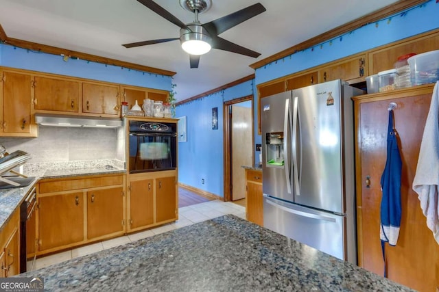 kitchen with light tile patterned flooring, stainless steel fridge, ornamental molding, black oven, and decorative backsplash