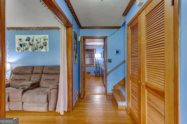 hall with ornamental molding and light hardwood / wood-style flooring