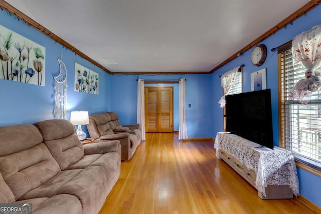 living room featuring light wood-type flooring, ornamental molding, and a wealth of natural light