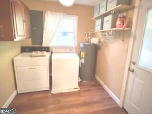 laundry area with electric water heater, wood-type flooring, cabinets, and independent washer and dryer