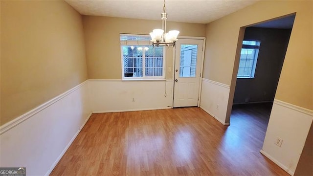 unfurnished dining area featuring a chandelier and hardwood / wood-style floors