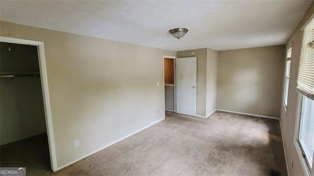 unfurnished bedroom with a spacious closet, a closet, and light colored carpet