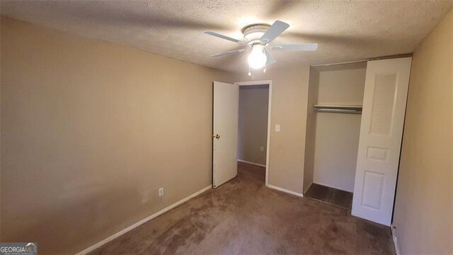 unfurnished bedroom with a closet, dark carpet, a textured ceiling, and ceiling fan