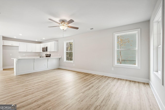 unfurnished living room featuring ceiling fan and light hardwood / wood-style flooring