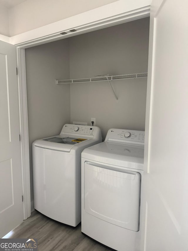 laundry area featuring hardwood / wood-style flooring and separate washer and dryer