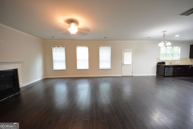 unfurnished living room with ornamental molding, dark wood-type flooring, sink, and ceiling fan with notable chandelier