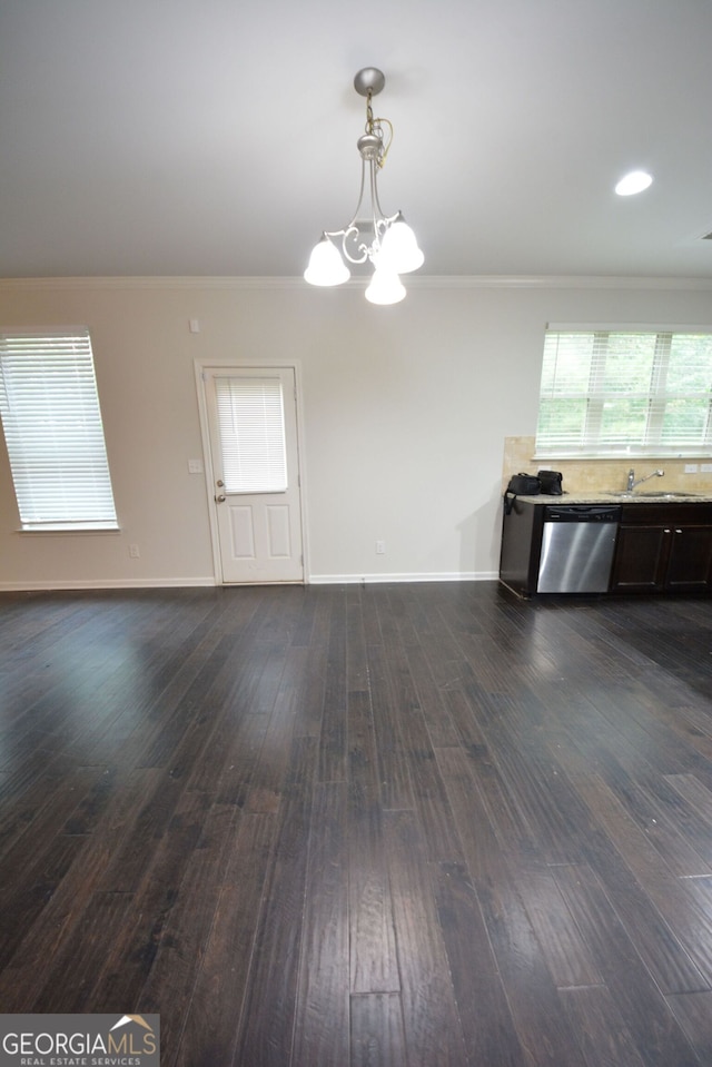 unfurnished dining area featuring ornamental molding, a notable chandelier, dark wood-type flooring, and sink