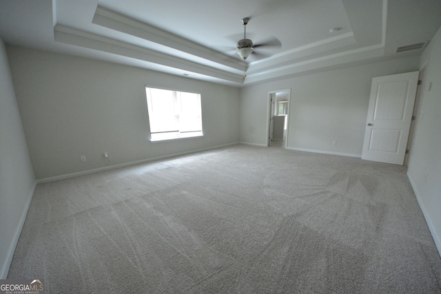 empty room featuring ceiling fan, light colored carpet, and a tray ceiling